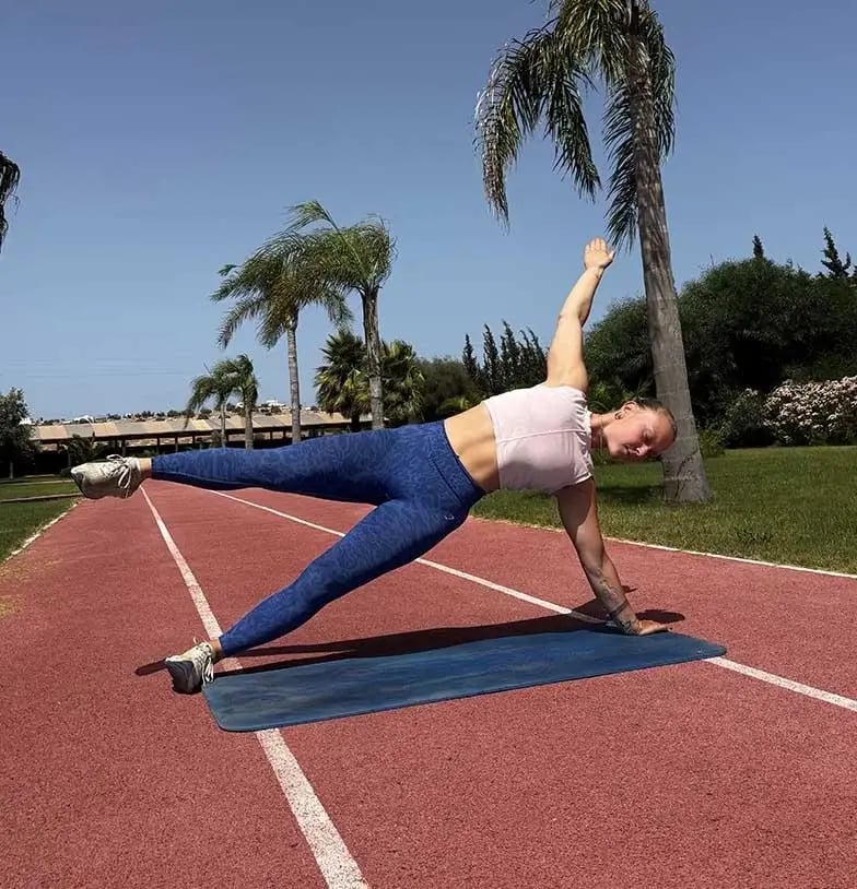 Une participante pratique un exercice de gainage en extérieur sur un tapis