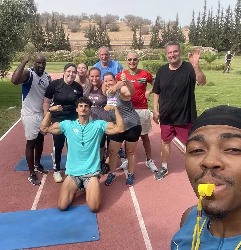 Des participants et leurs encadrants réunis sur une piste sportive extérieure